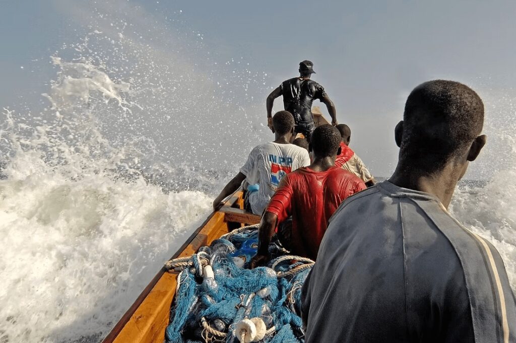Fishermen crash through a wave near one of the best surf spots in Ghana