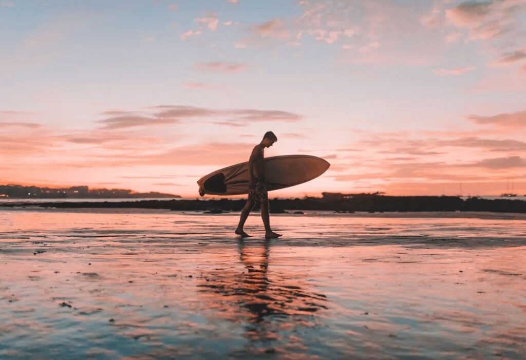 A spectacular sunset behind a silhouetted surfer at one of the best surf spots in Colombia