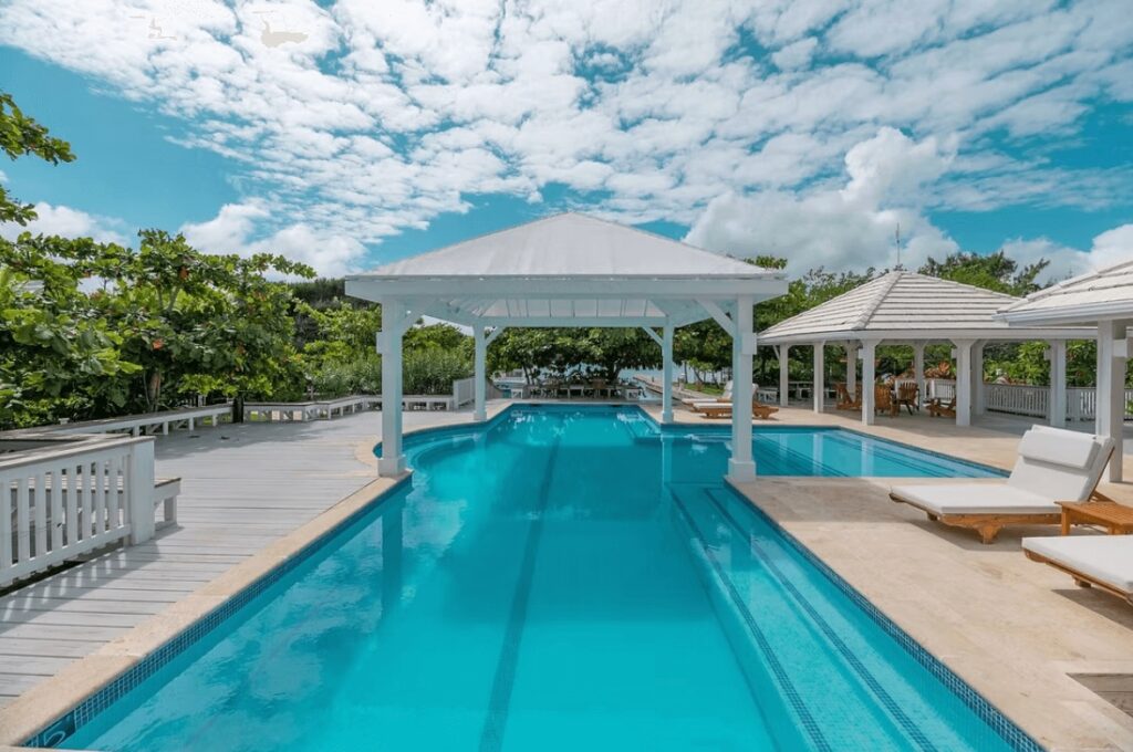 A white pavilion over the sparkling swimming pool at Barefoot Cay Resort, one of the best eco-friendly dive resorts on Roatan