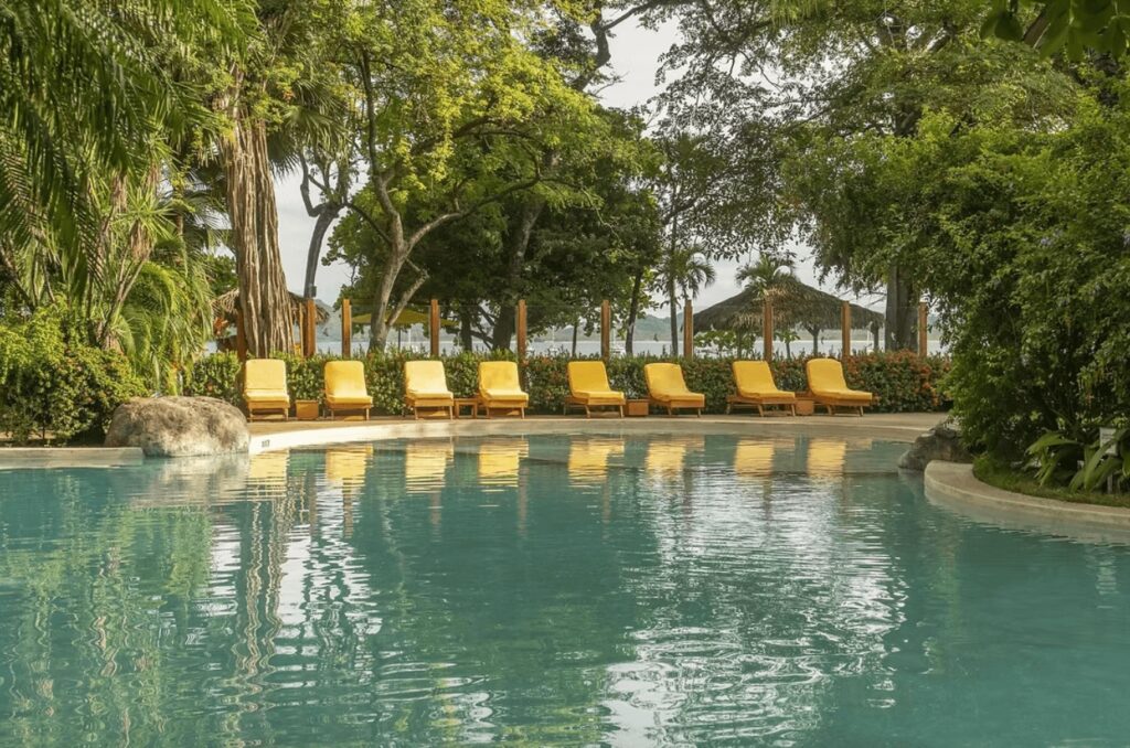 Yellow sun loungers beside the lagoon-like pool at Capitán Suizo Beachfront Boutique Hotel in Tamarindo