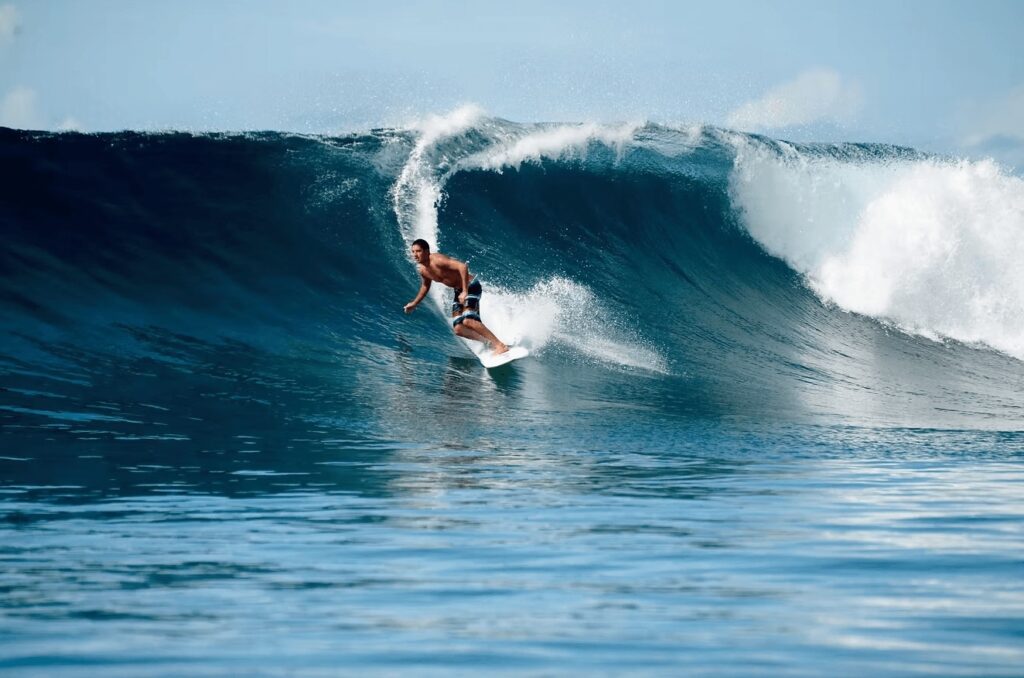 A surfer rides a wave at Maqai Beach Eco Resort, a STOKE-certified property in Fiji 
