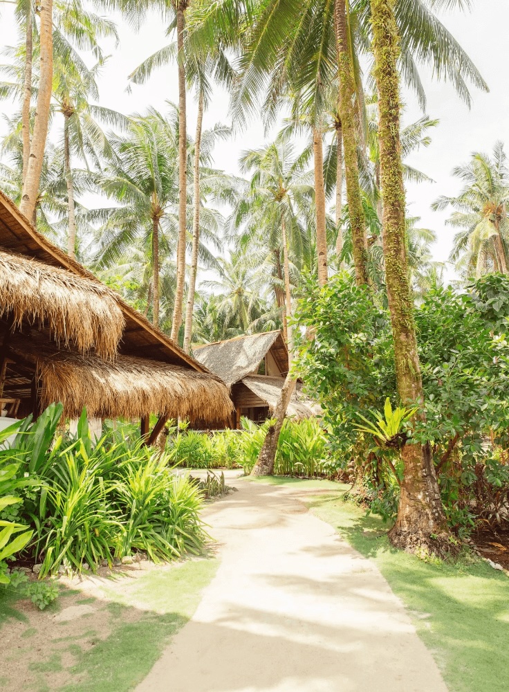 Thatched roof bungalows dot the grounds of the Harana Surf Resort, a STOKE-certified property in Siargao 