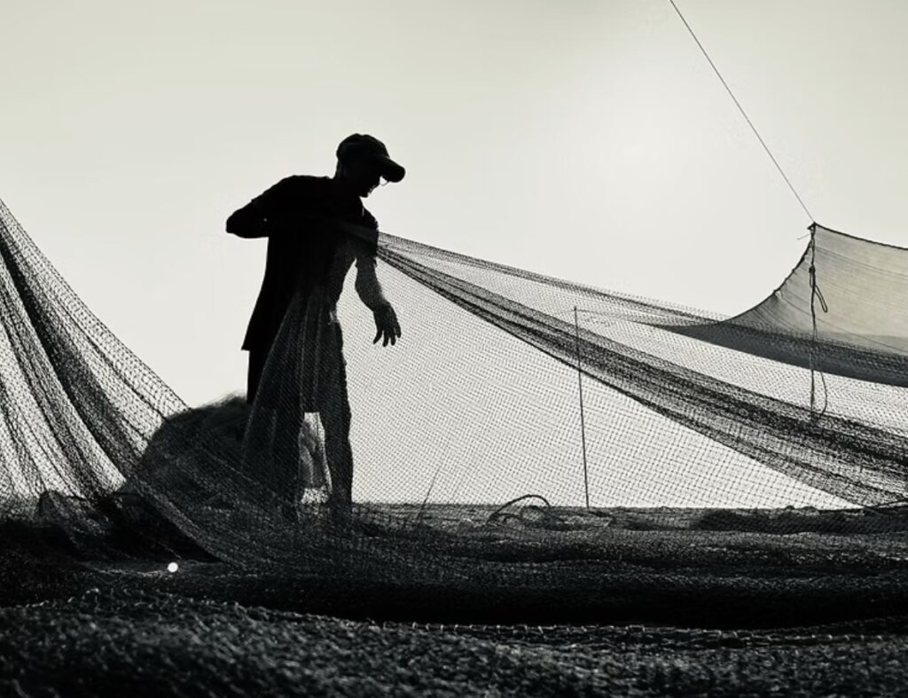 What are ghost nets? A fisherman mends a fishing net on a beach