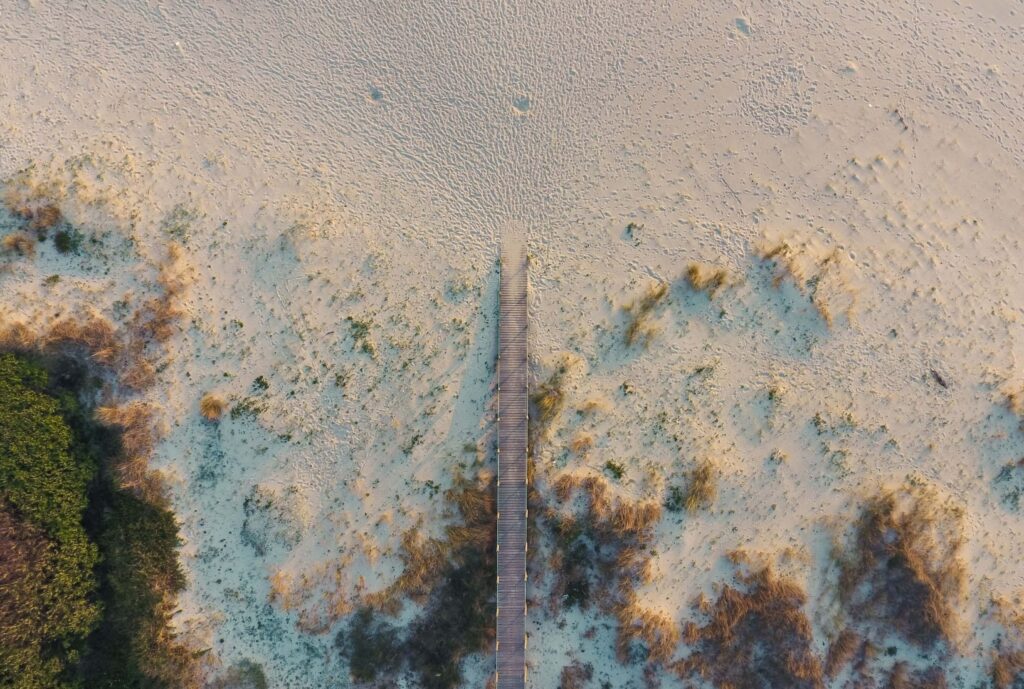 A wooden boardwalk leads onto the sand at Hotel FeelViana
