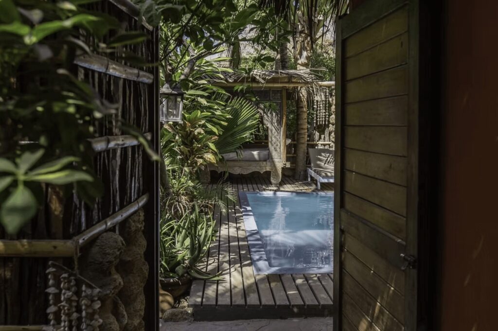 A wooden gate leads to the outdoor pool at La Maison Eco House & Yoga in Mancora 