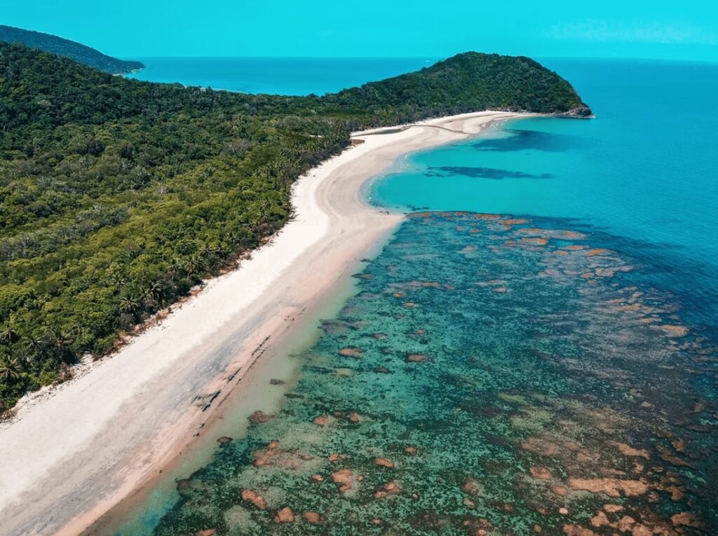 An elevated view of a white sandy beach along the edge of the Great Barrier Reef