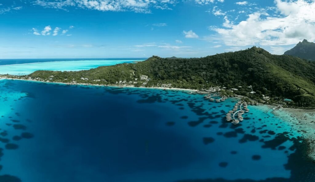 Overwater bungalows extend from a coastline in Bora Bora, French Polynesia