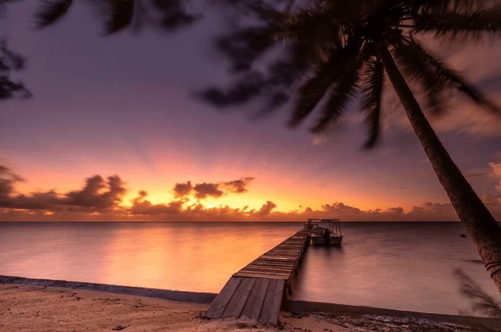 A jetty extends into the water at sunset in French Polynesia