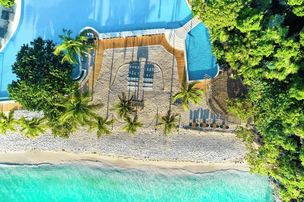 An aerial view of where the pool meets the beach at the Kimpton Grand Roatan Resort & Spa