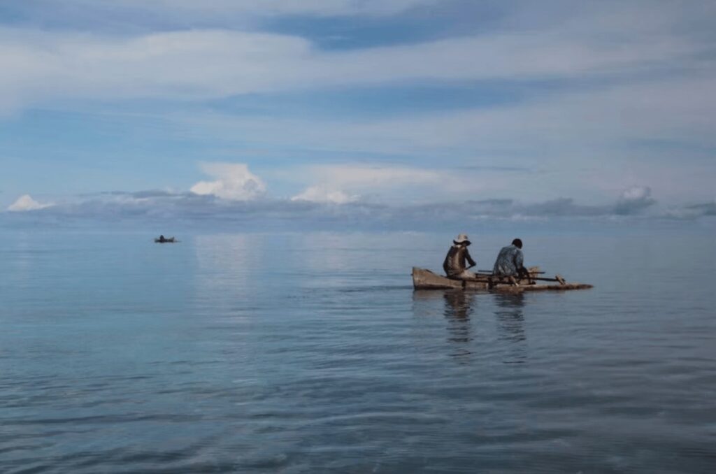 Two Madagascan fishermen in a wooden boat off the coast of Nosy Be