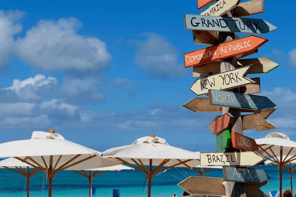 Directional signs alongside beach umbrellas at an eco-friendly resort in Turks and Caicos