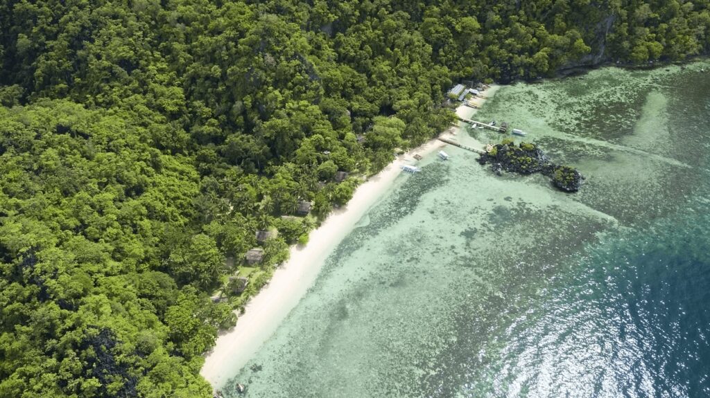An aerial view of a white sandy beach at Sangat Island Resort, an eco-dive resort in Coron, Philippines 