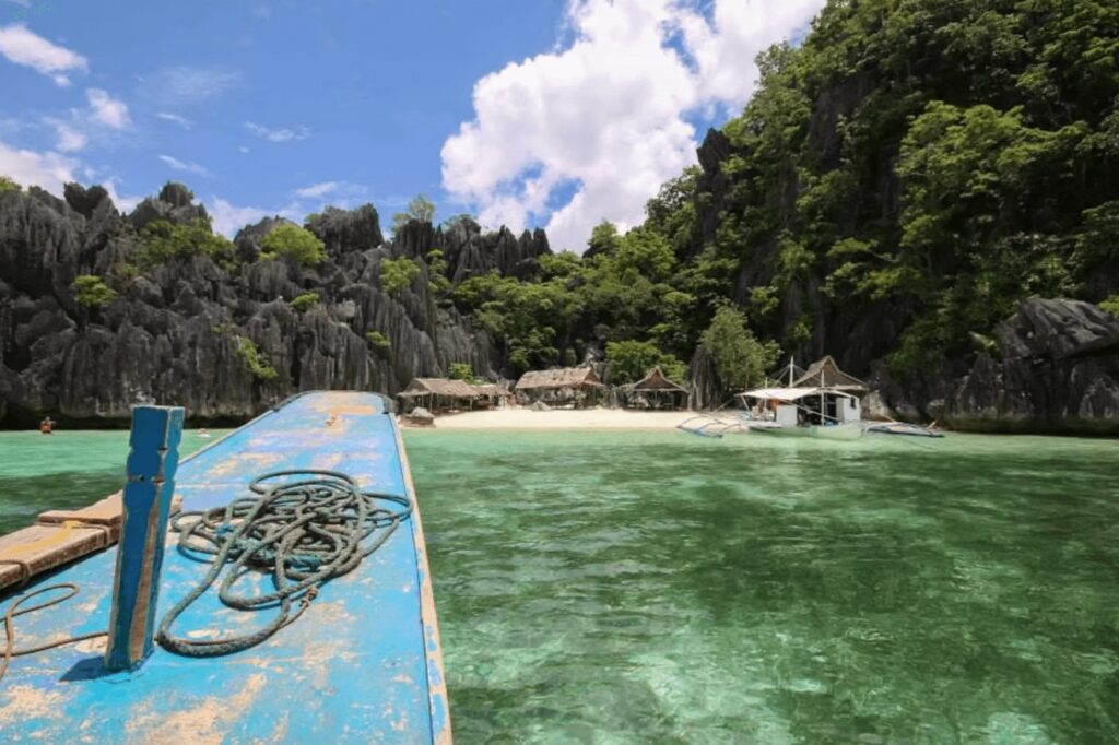 Scuba diving in the Philippines: A blue wooden boat moored beside an idyllic island