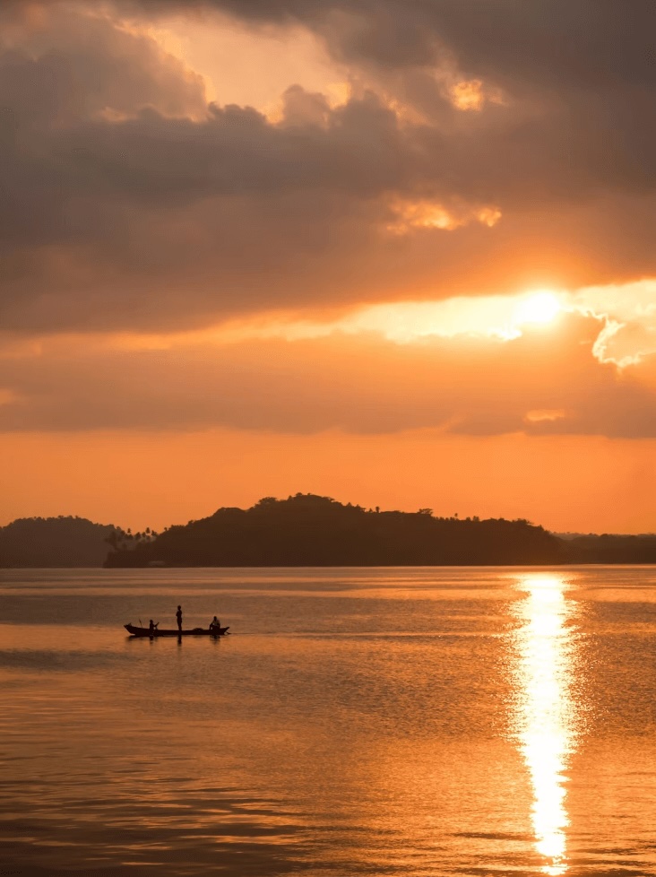 Surfing in the Andaman Islands: A silhouette of a fishing boat at sunset