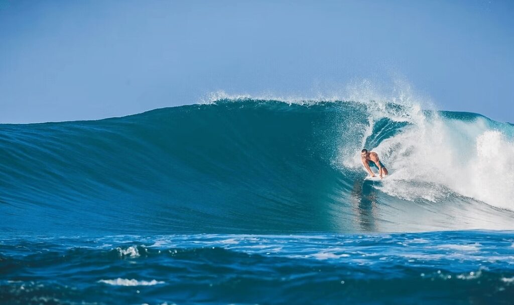 A surfer rides a wave in West Sumbawa near Kirana Retreat, an eco-friendly resort