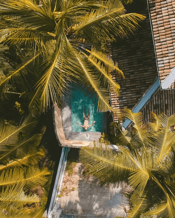 A bird's eye view of a guest floating in a pool at an eco-friendly surf resort in Sri Lanka