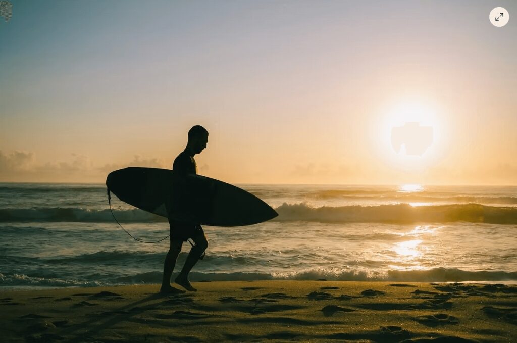 World Surfing Reserves: A silhouette of a surfer walking along a beach at sunset