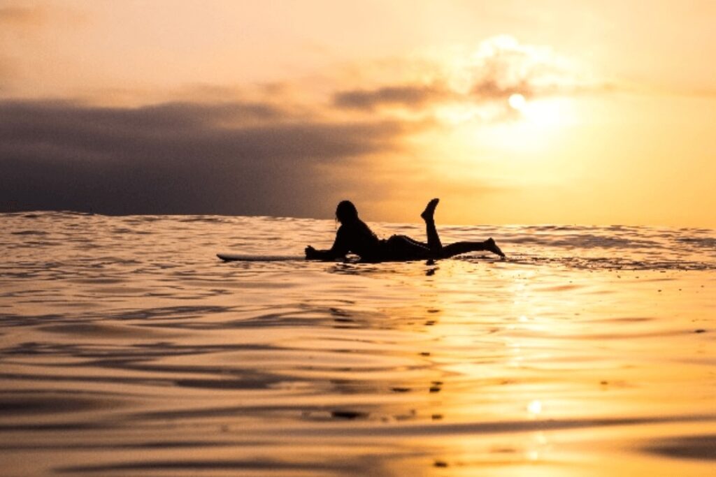 How to be an eco-friendly surfer: A silhouette of a longboarder at sunset