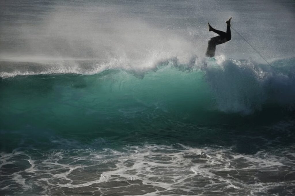 The environmental impacts of neoprene wetsuits: A surfer head dives over a wave