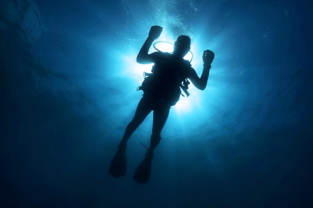 How to be a responsible diver: A silhouette of a diver at the water's surface