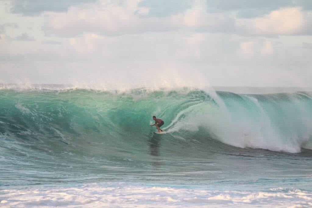 A surfer rides a barrelling wave