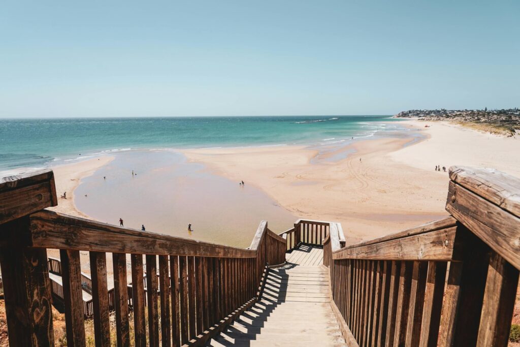 A wooden walkway descends to a sandy beach in Australia