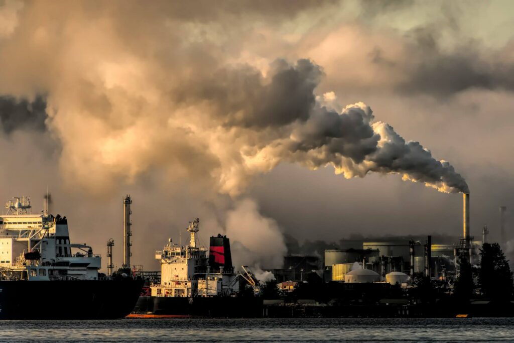Smoke billows from a chimney at an industrial port