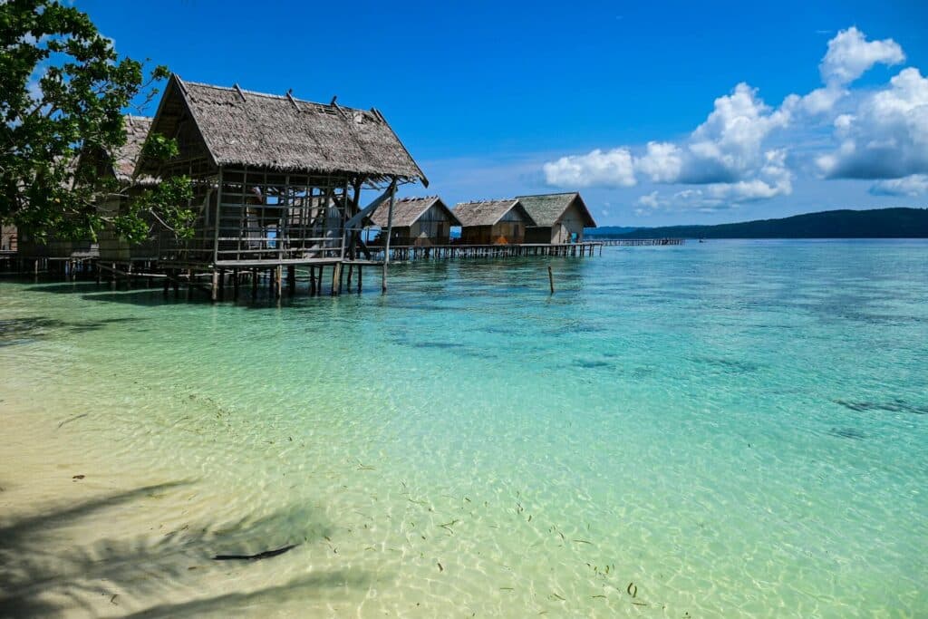 Thatched roof overwater bungalows at a homestay in Raja Ampat
